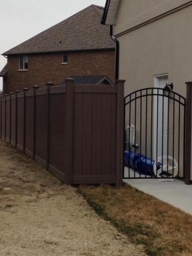 Weathered blend vinyl fence with arched metal gate